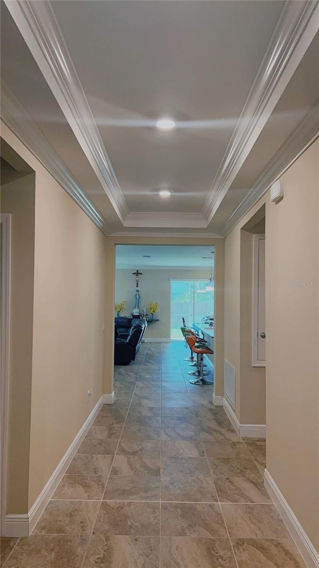 hall featuring baseboards, visible vents, a raised ceiling, and crown molding