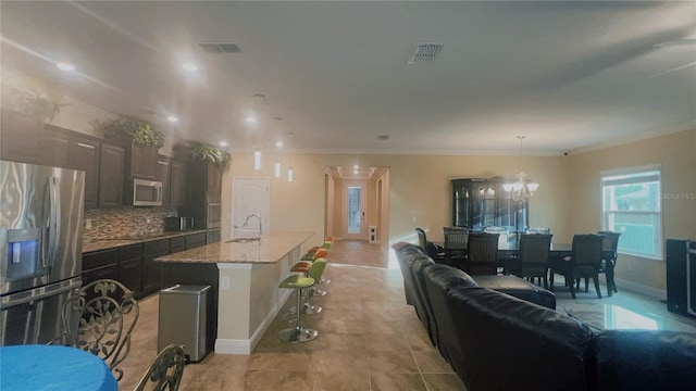 kitchen with visible vents, appliances with stainless steel finishes, a sink, crown molding, and backsplash