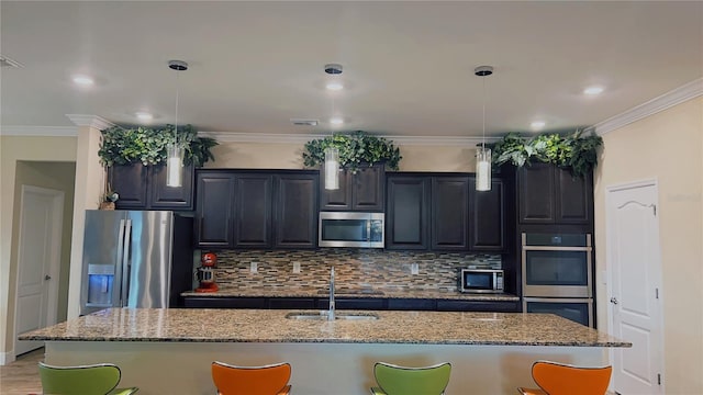 kitchen with ornamental molding, appliances with stainless steel finishes, an island with sink, and backsplash