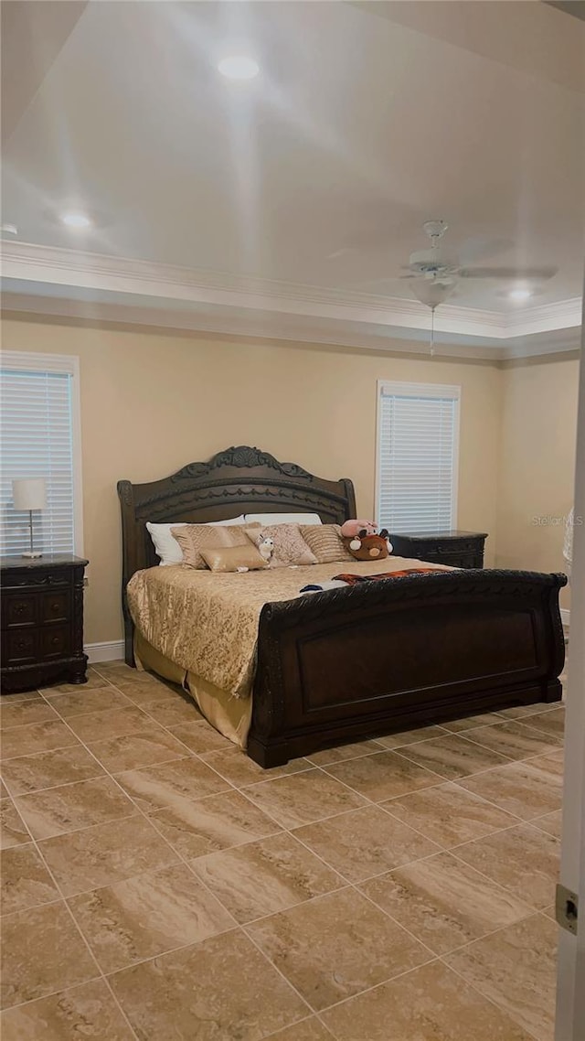 bedroom featuring ornamental molding, a tray ceiling, ceiling fan, and baseboards