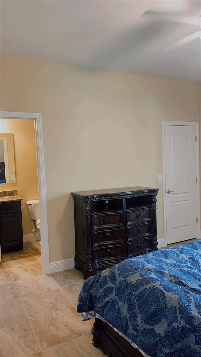 bedroom with baseboards, ensuite bath, and light tile patterned flooring