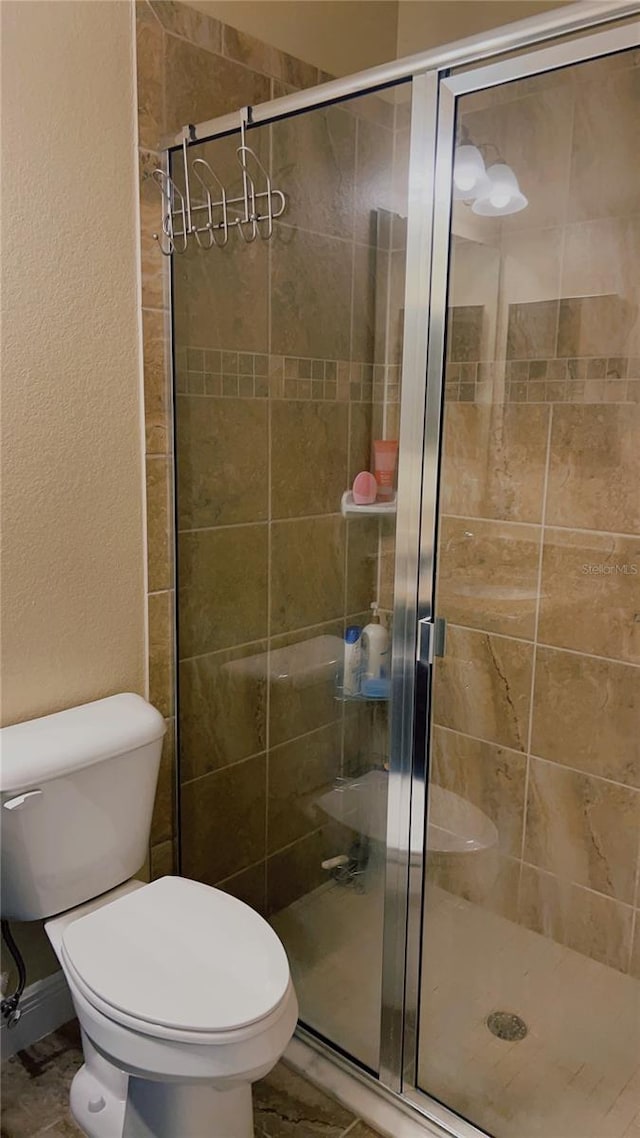 full bath featuring a stall shower, a textured wall, and toilet