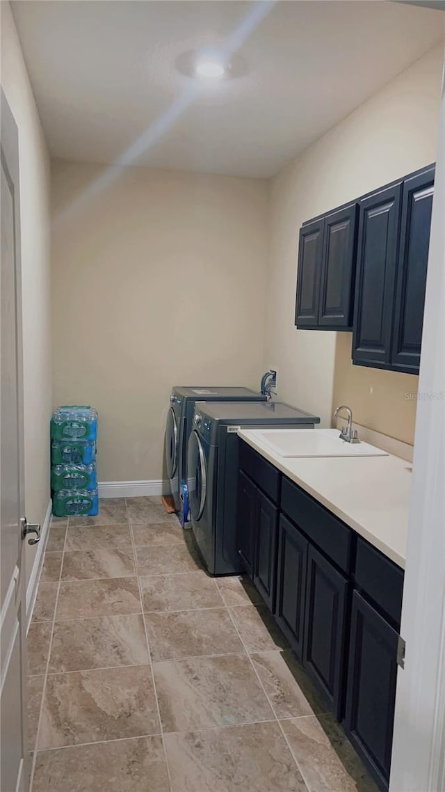 laundry area featuring a sink, cabinet space, baseboards, and washer and dryer