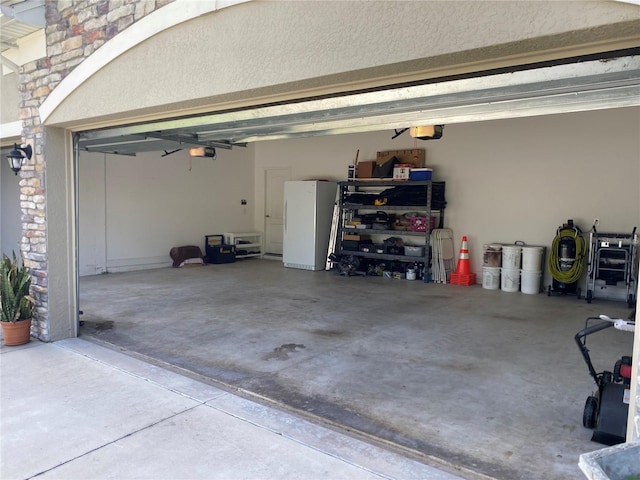 garage with a garage door opener and freestanding refrigerator