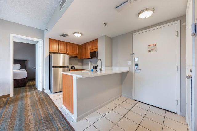 kitchen featuring visible vents, light countertops, light tile patterned floors, a peninsula, and stainless steel appliances