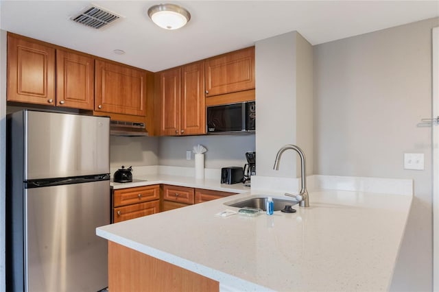 kitchen with visible vents, black appliances, under cabinet range hood, a sink, and a peninsula