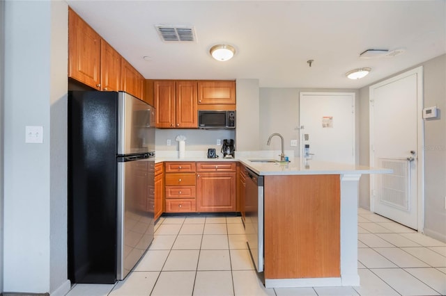 kitchen featuring visible vents, a peninsula, a sink, stainless steel appliances, and light countertops