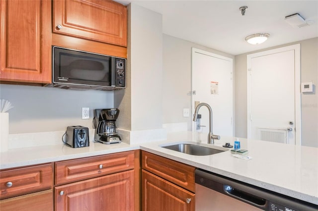 kitchen featuring brown cabinets, a sink, stainless steel dishwasher, a peninsula, and black microwave