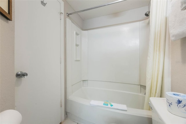 bathroom with toilet, a textured wall, and shower / bath combo with shower curtain