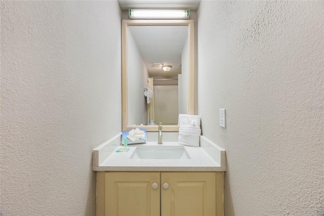 bathroom with an enclosed shower, vanity, and a textured wall