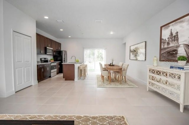 kitchen featuring light countertops, recessed lighting, light tile patterned floors, stainless steel appliances, and dark brown cabinetry