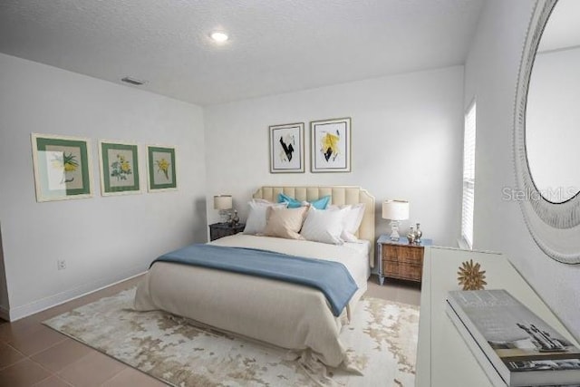 bedroom with baseboards, a textured ceiling, and visible vents