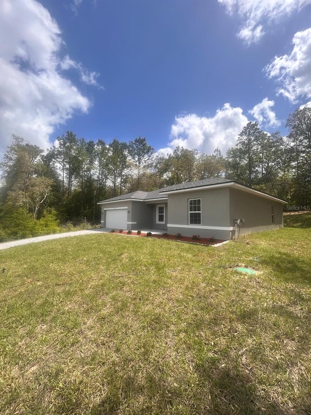 9451 N Emellia Ave, Citrus Springs, FL 34433 - back of house featuring a garage, driveway, a yard, stucco siding, and view of scattered trees