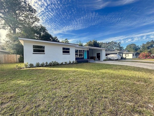 view of front of property with an attached carport, concrete driveway, fence, and a front lawn