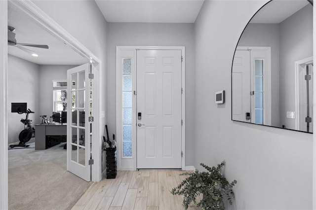 foyer with wood finished floors, a ceiling fan, and baseboards