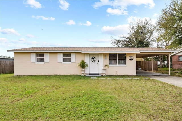 ranch-style home featuring driveway, concrete block siding, an attached carport, fence, and a front yard