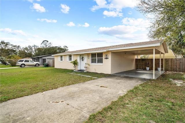 ranch-style home featuring concrete block siding, fence, an attached carport, driveway, and a front lawn