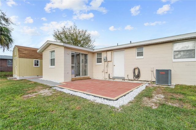 back of house featuring an outbuilding, a patio, a storage unit, a lawn, and central AC