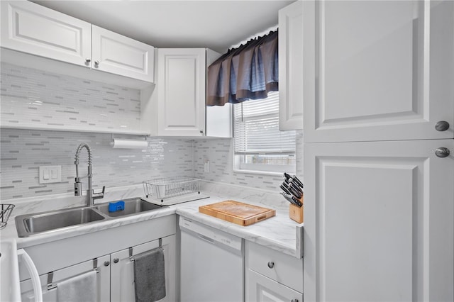 kitchen featuring dishwasher, tasteful backsplash, a sink, and white cabinets