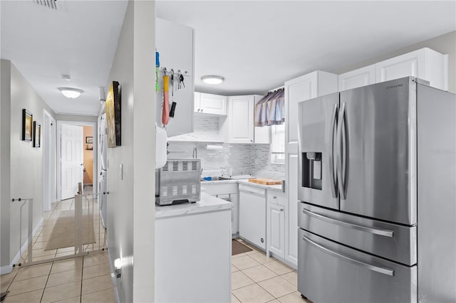 kitchen with light tile patterned floors, stainless steel fridge with ice dispenser, white dishwasher, light countertops, and white cabinetry