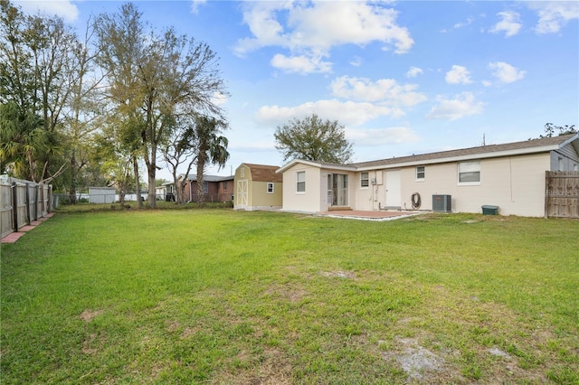 back of property with an outbuilding, a yard, a patio area, a shed, and a fenced backyard