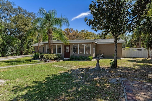 view of front of house featuring stucco siding, a front yard, and fence