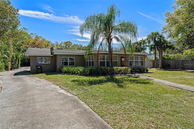 ranch-style home with stucco siding, a front lawn, and fence