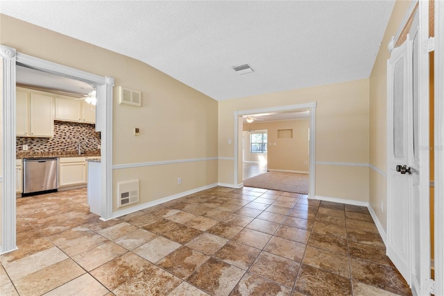 spare room with visible vents, baseboards, ceiling fan, lofted ceiling, and a textured ceiling