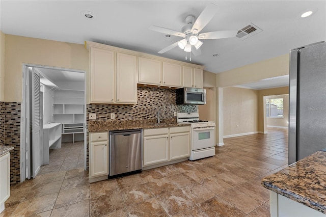 kitchen with visible vents, a sink, decorative backsplash, cream cabinetry, and appliances with stainless steel finishes