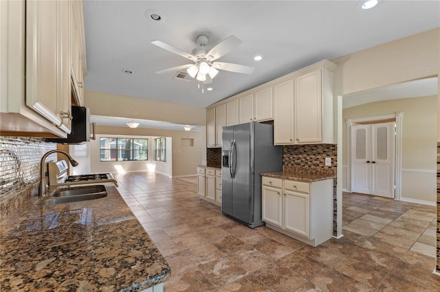 kitchen with a sink, backsplash, stainless steel fridge with ice dispenser, baseboards, and ceiling fan