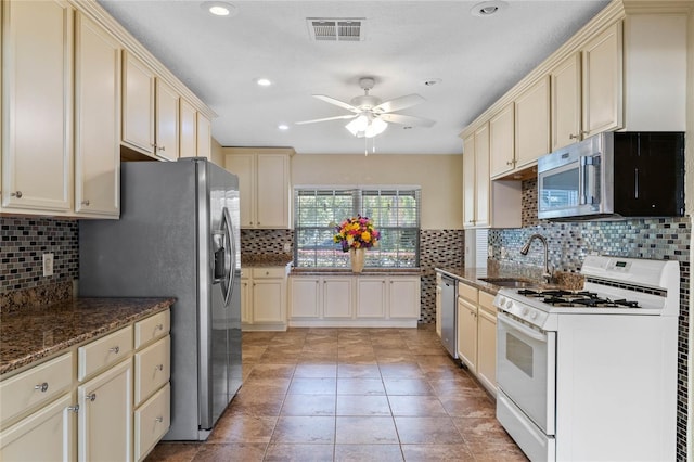 kitchen with visible vents, cream cabinets, stainless steel appliances, and a sink