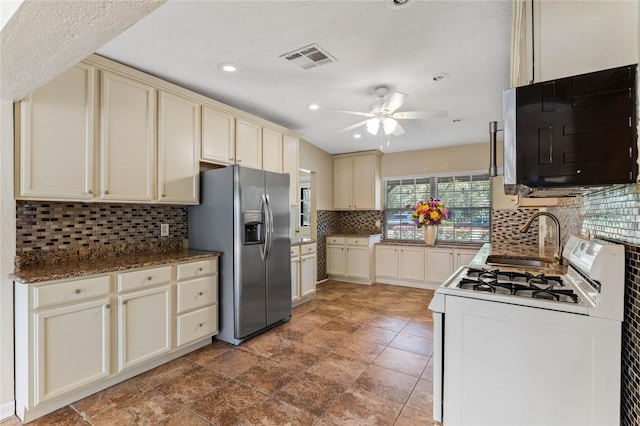 kitchen with visible vents, white gas stove, stainless steel fridge with ice dispenser, a sink, and cream cabinets