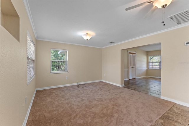 carpeted spare room featuring visible vents, a ceiling fan, baseboards, and ornamental molding