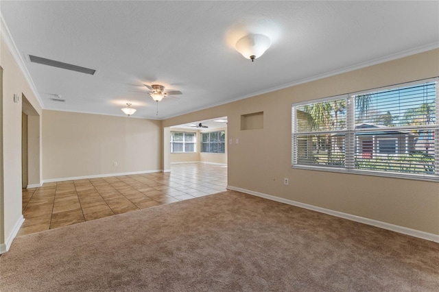 tiled empty room with visible vents, carpet flooring, crown molding, and ceiling fan