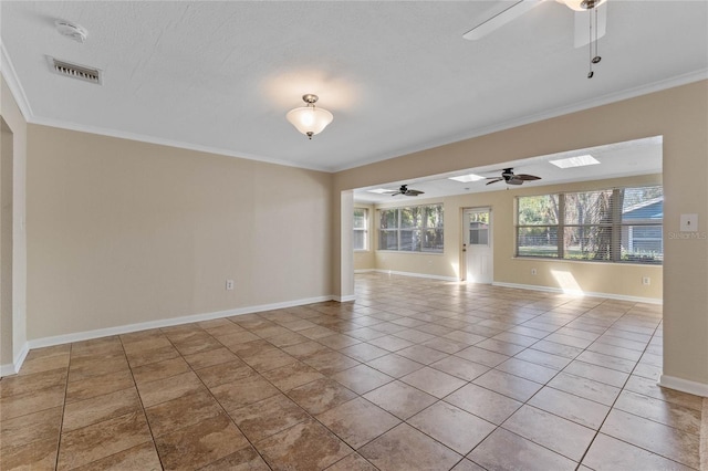 empty room with light tile patterned flooring, visible vents, crown molding, and baseboards