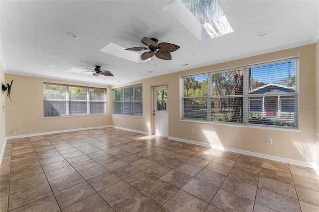 empty room featuring tile patterned flooring, a skylight, baseboards, and ceiling fan