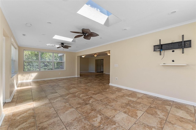 unfurnished room with a ceiling fan, visible vents, baseboards, a skylight, and ornamental molding