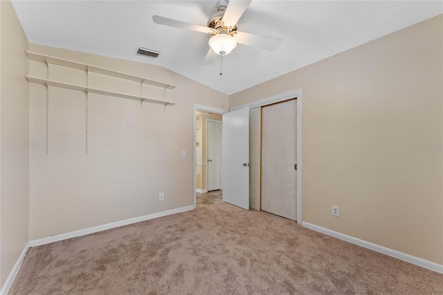 unfurnished bedroom with visible vents, baseboards, lofted ceiling, carpet flooring, and a closet