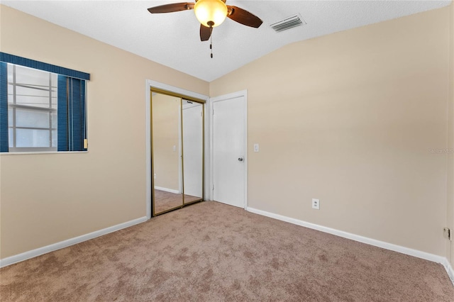 unfurnished bedroom featuring visible vents, lofted ceiling, carpet, and baseboards