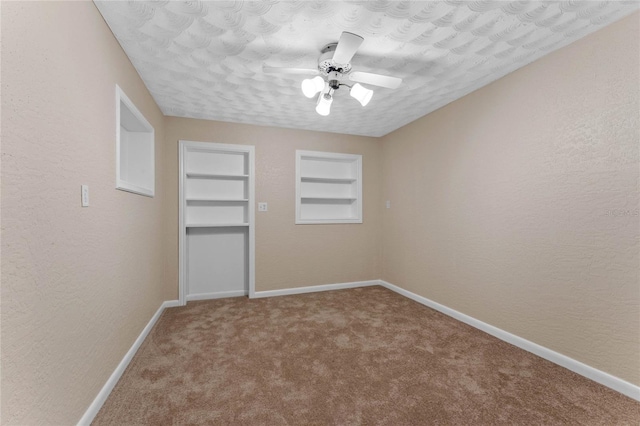 unfurnished room with built in features, baseboards, ceiling fan, and carpet flooring