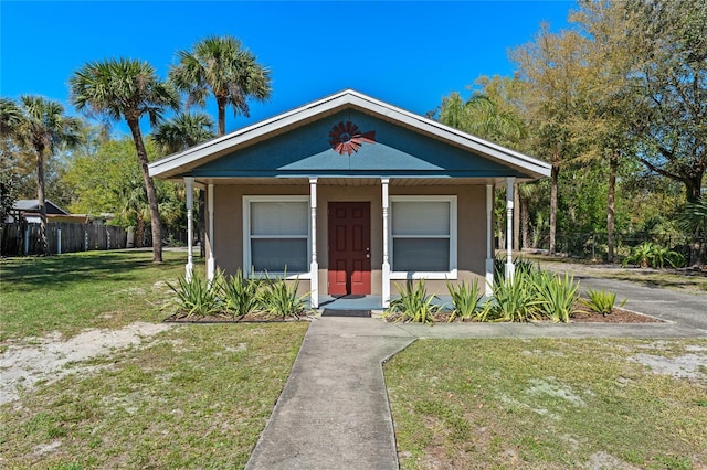 view of front of house featuring stucco siding, a porch, a front yard, and fence