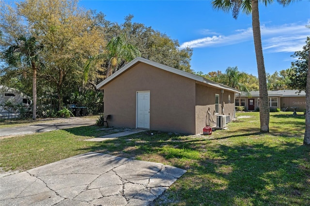 view of side of property with central air condition unit, stucco siding, and a lawn