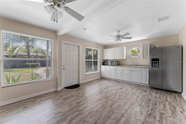 kitchen with light wood finished floors, visible vents, stainless steel refrigerator with ice dispenser, white cabinets, and a sink