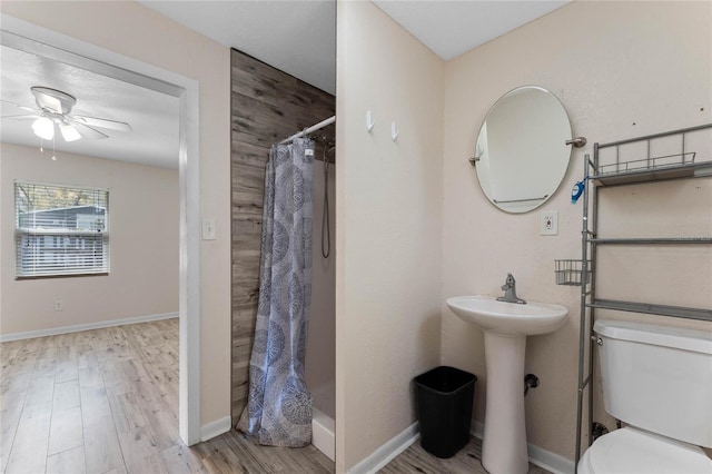 bathroom featuring curtained shower, baseboards, toilet, wood finished floors, and a ceiling fan