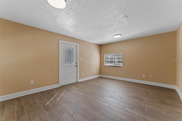 unfurnished room with dark wood-type flooring, baseboards, and a textured ceiling