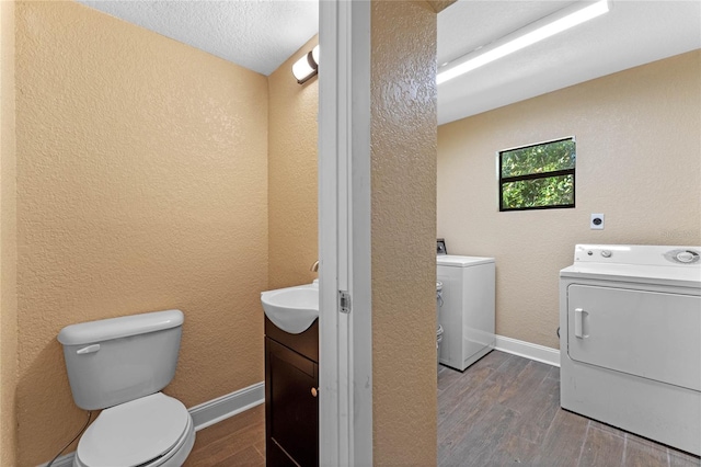 bathroom featuring wood finished floors, toilet, and washing machine and dryer