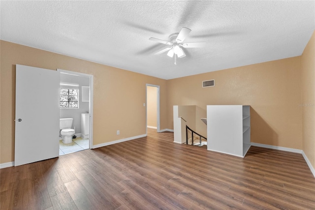 interior space with visible vents, a textured ceiling, baseboards, and wood finished floors