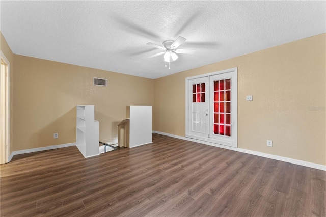 unfurnished room with baseboards, visible vents, dark wood-style flooring, and a textured ceiling