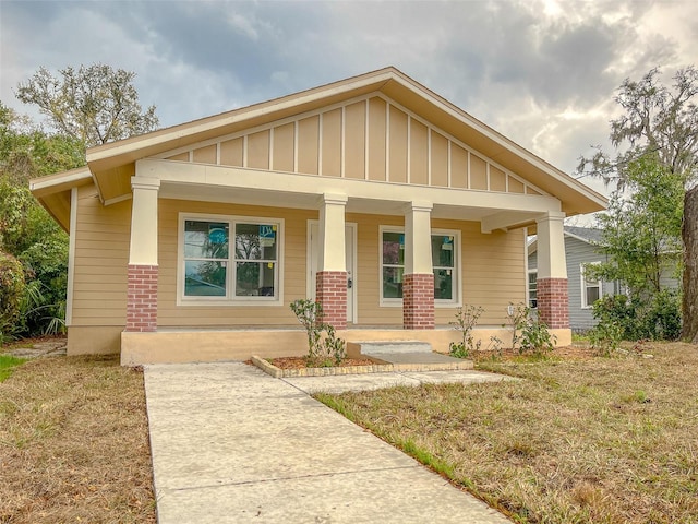 craftsman-style home with a porch, board and batten siding, and brick siding