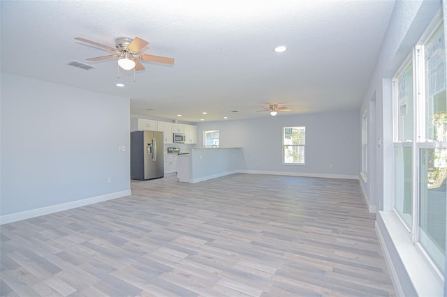 unfurnished living room with baseboards, a textured ceiling, visible vents, and a ceiling fan